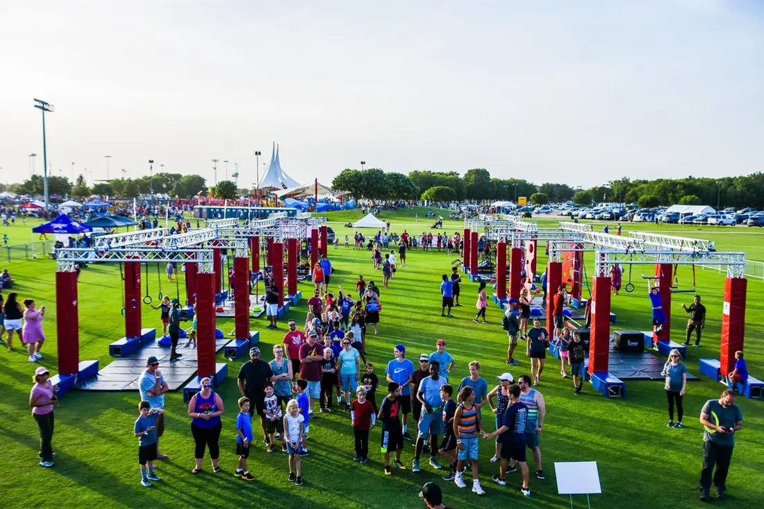 Overhead view of a mobile ninja obstacle course at an outdoor festival with a large crowd